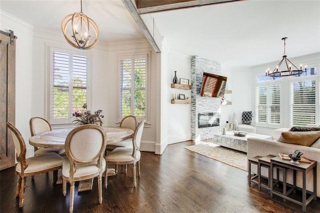 dining room with dark wood-type flooring, a fireplace, a notable chandelier, and a barn door