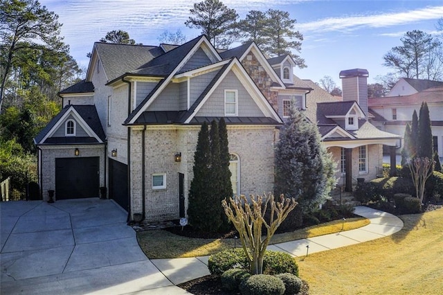 view of front facade with metal roof, a garage, brick siding, concrete driveway, and a standing seam roof