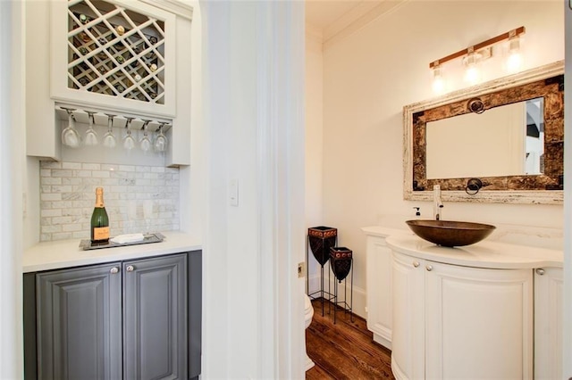 bar with a dry bar, dark wood-style floors, backsplash, and a sink