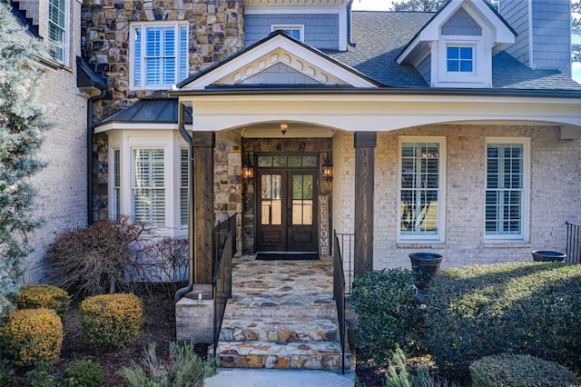 property entrance featuring brick siding, roof with shingles, a porch, and french doors