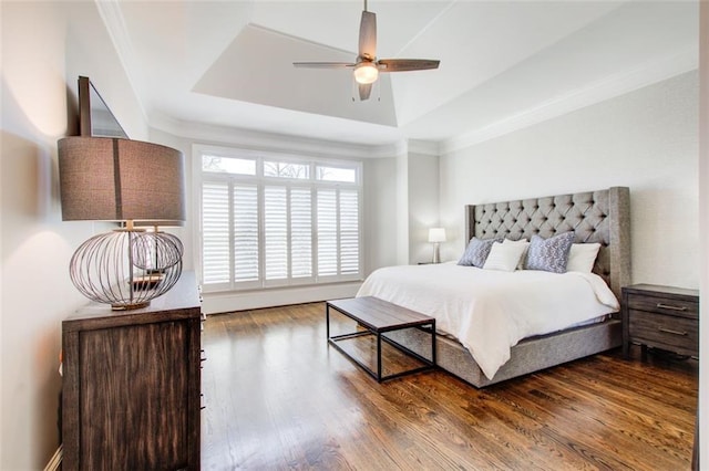 bedroom with a ceiling fan, a tray ceiling, wood finished floors, and ornamental molding