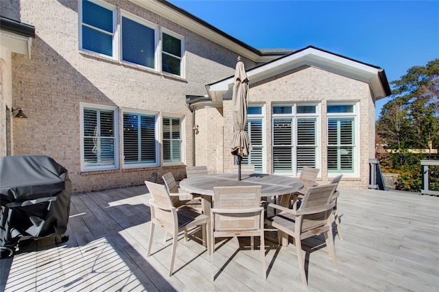 wooden deck with outdoor dining area and a grill