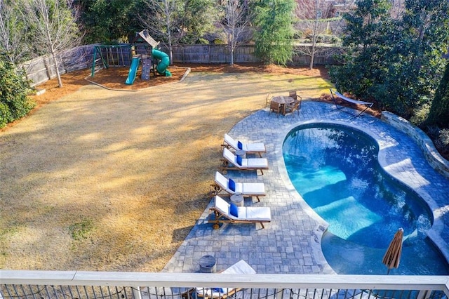 view of pool with a playground and a fenced backyard