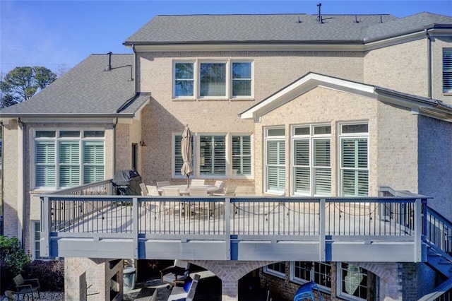 rear view of property featuring roof with shingles, a carport, and brick siding