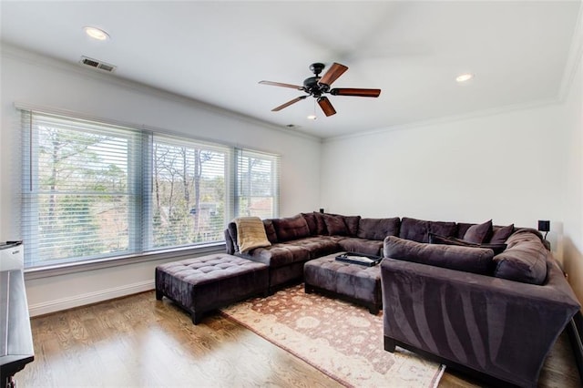 living room with ornamental molding, visible vents, light wood-style flooring, and baseboards