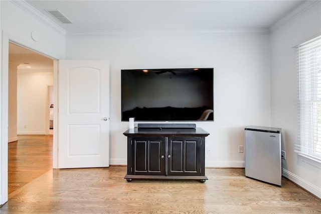 living room featuring ornamental molding, baseboards, visible vents, and light wood finished floors