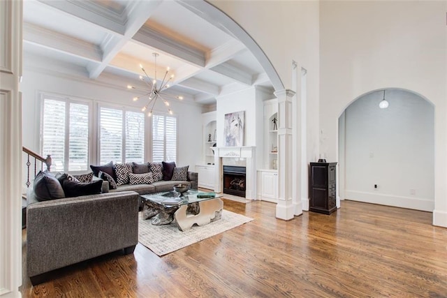 living area with arched walkways, wood finished floors, beam ceiling, and a notable chandelier