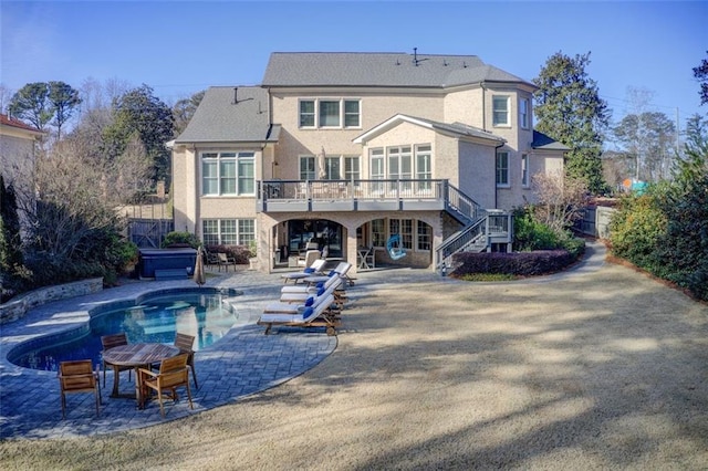 back of house with stucco siding, an outdoor pool, a patio, and stairs