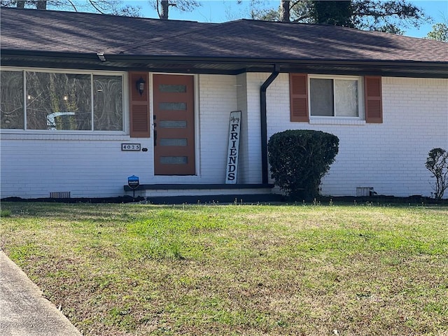 doorway to property with crawl space, brick siding, and a lawn