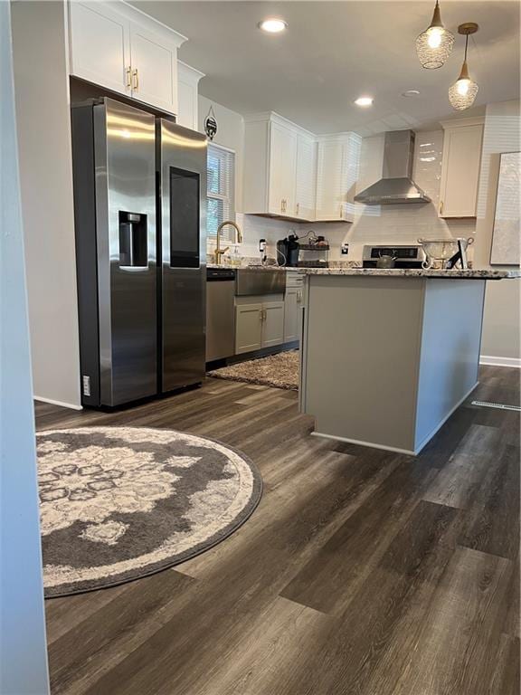 kitchen with white cabinets, stainless steel appliances, wall chimney exhaust hood, and dark wood-style flooring