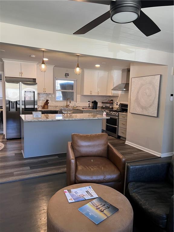 living area featuring ceiling fan and dark wood finished floors