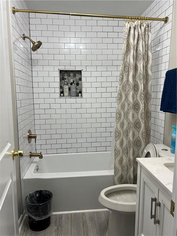 bathroom featuring shower / tub combo with curtain, wood finished floors, vanity, and toilet