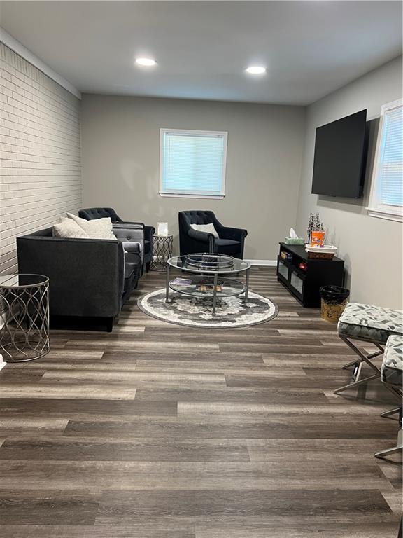 living area with recessed lighting, brick wall, baseboards, and wood finished floors