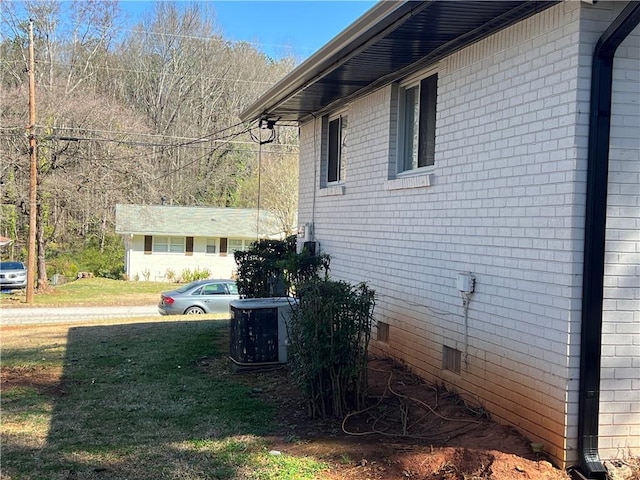 view of side of home with crawl space, a lawn, central AC, and brick siding