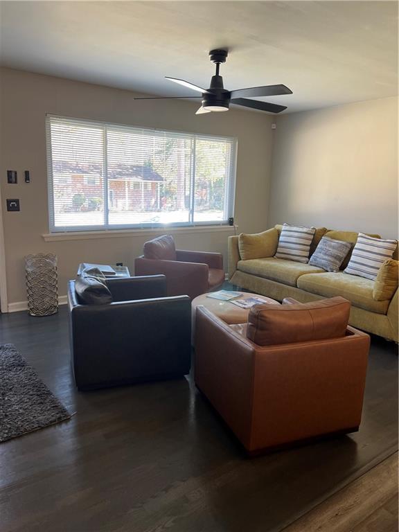 living room with baseboards, ceiling fan, and dark wood-style flooring