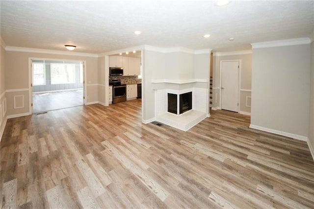 unfurnished living room featuring light hardwood / wood-style floors, ornamental molding, and a multi sided fireplace