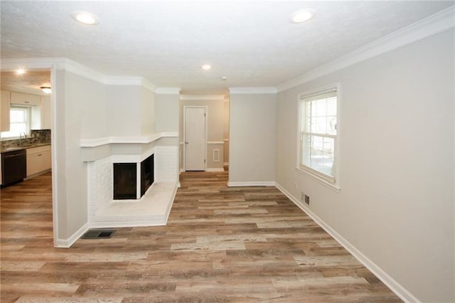 unfurnished living room with ornamental molding, sink, wood-type flooring, and a multi sided fireplace