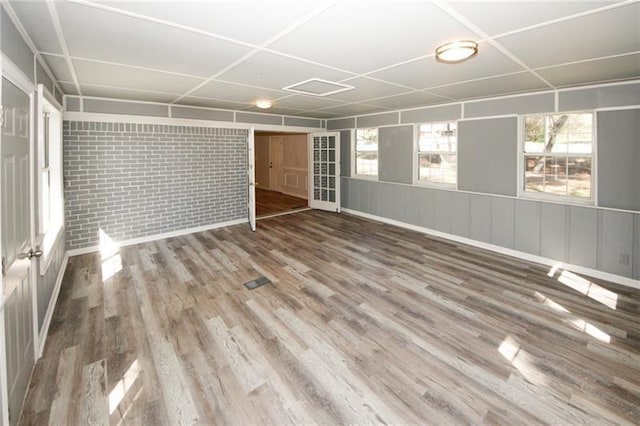 unfurnished room featuring wood-type flooring and brick wall