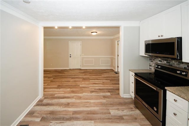 kitchen with white cabinetry, stainless steel appliances, light wood-type flooring, and ornamental molding