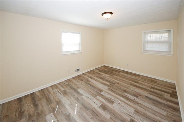 empty room with hardwood / wood-style flooring and a wealth of natural light