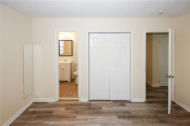 unfurnished bedroom with tile patterned flooring, a closet, and ensuite bath