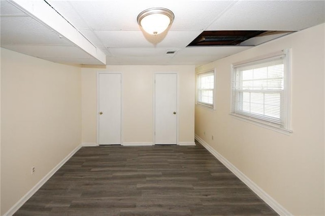 spare room featuring dark hardwood / wood-style flooring and a paneled ceiling