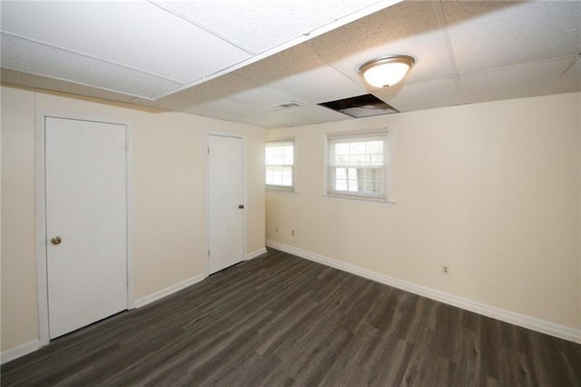 interior space featuring dark wood-type flooring and a drop ceiling