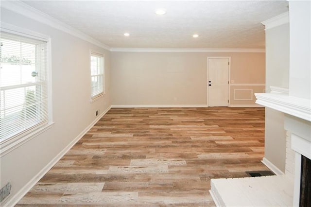 unfurnished room featuring crown molding, wood-type flooring, and a brick fireplace