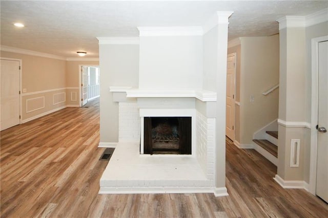 unfurnished living room featuring crown molding, hardwood / wood-style flooring, and a brick fireplace