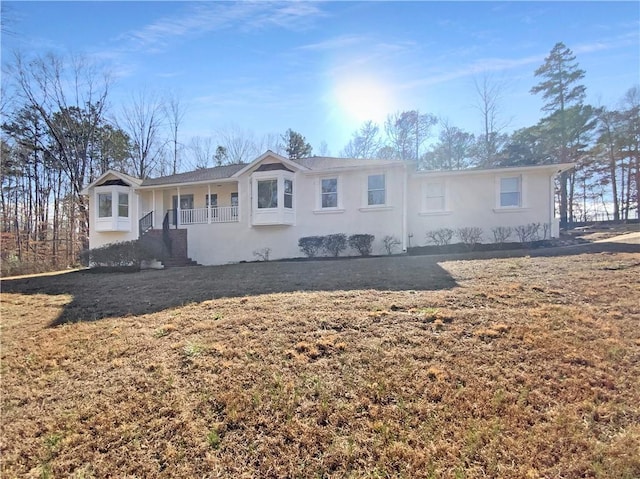 view of front facade with stucco siding, a porch, and a front lawn