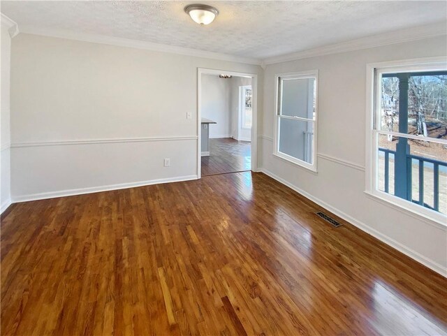 unfurnished room with a wealth of natural light, visible vents, a textured ceiling, and wood finished floors