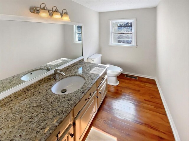 bathroom featuring visible vents, baseboards, toilet, vanity, and wood-type flooring