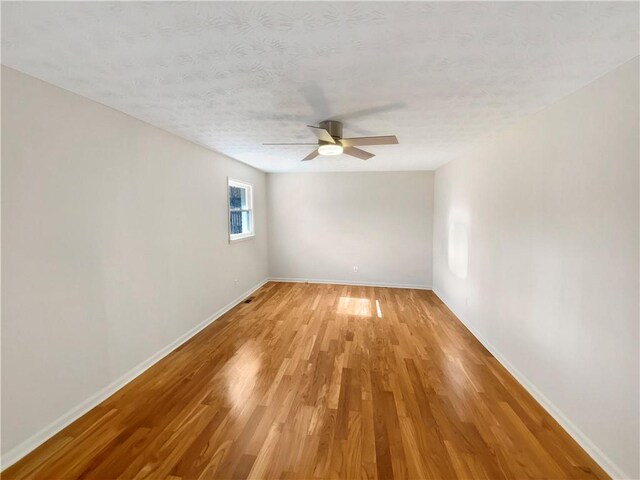 empty room featuring baseboards, ceiling fan, a textured ceiling, and light wood-style floors