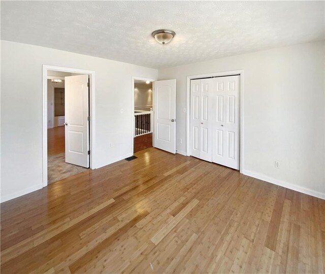 unfurnished bedroom with a closet, baseboards, a textured ceiling, and wood finished floors