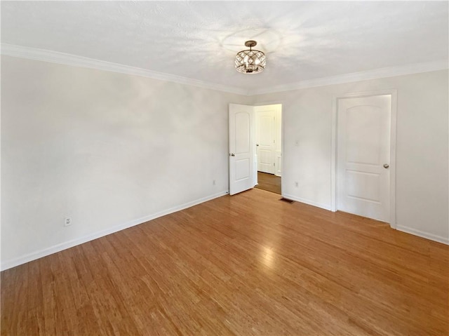 unfurnished room featuring visible vents, crown molding, an inviting chandelier, and wood finished floors