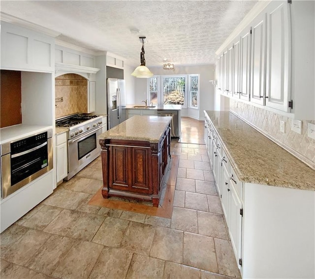 kitchen featuring a sink, light stone counters, backsplash, and stainless steel appliances