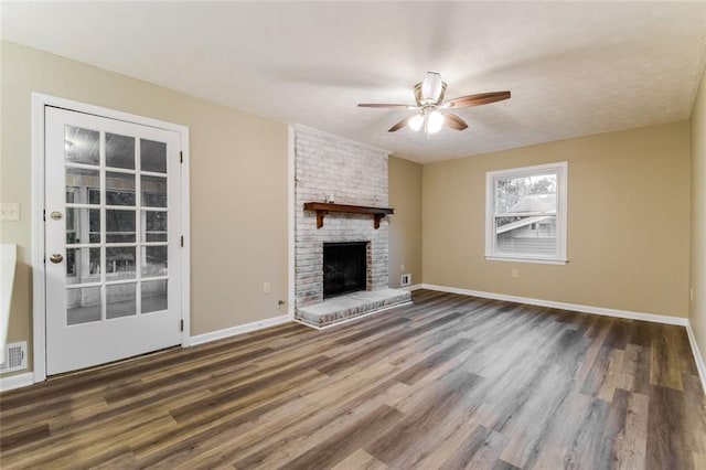 unfurnished living room featuring dark wood-type flooring, ceiling fan, and a brick fireplace