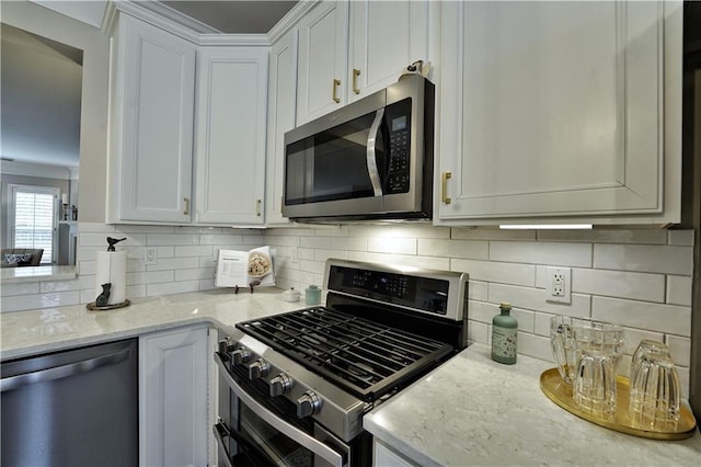 kitchen featuring white cabinets, light stone countertops, stainless steel appliances, and tasteful backsplash