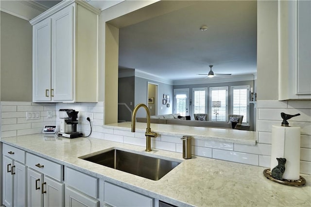 kitchen with white cabinets, ceiling fan, ornamental molding, and sink