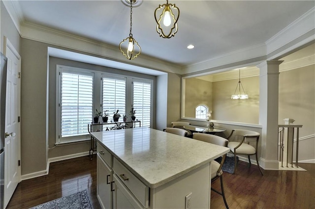 kitchen with dark hardwood / wood-style flooring, a center island, ornate columns, and hanging light fixtures