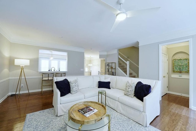 living area featuring baseboards, stairway, wood finished floors, and crown molding