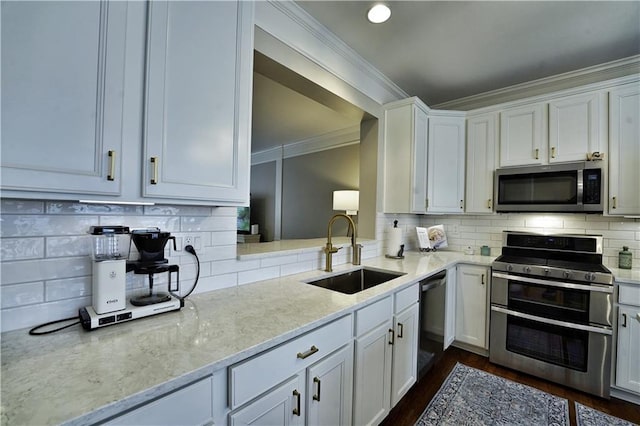 kitchen featuring light stone countertops, white cabinetry, sink, stainless steel appliances, and tasteful backsplash