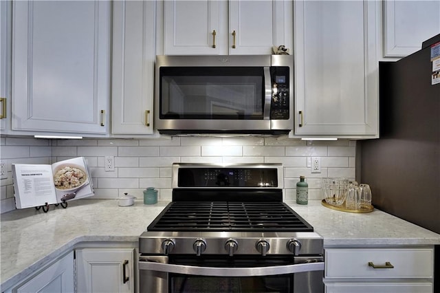 kitchen with white cabinets, decorative backsplash, stainless steel appliances, and light stone counters