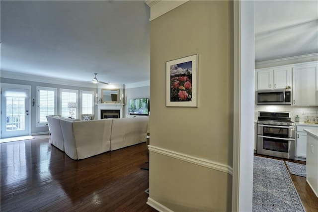 living room with dark hardwood / wood-style floors, ceiling fan, and ornamental molding