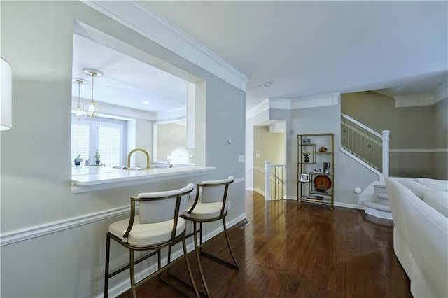 interior space with sink, a kitchen breakfast bar, dark hardwood / wood-style flooring, kitchen peninsula, and crown molding