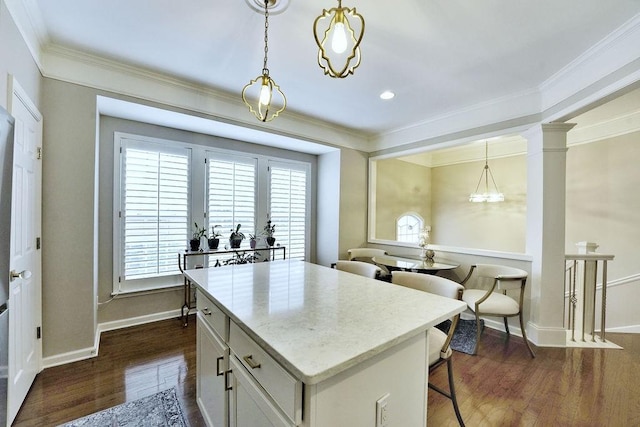 kitchen featuring light countertops, a center island, dark wood finished floors, decorative light fixtures, and crown molding