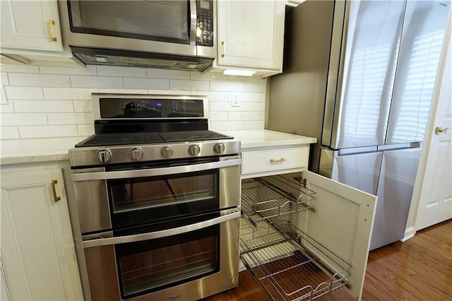 kitchen with white cabinets, backsplash, stainless steel appliances, and dark wood-type flooring