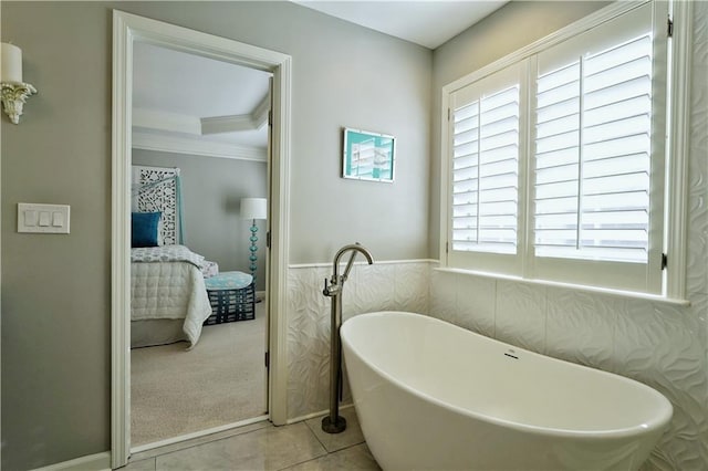 bathroom featuring tile patterned floors, a bathtub, crown molding, and tile walls