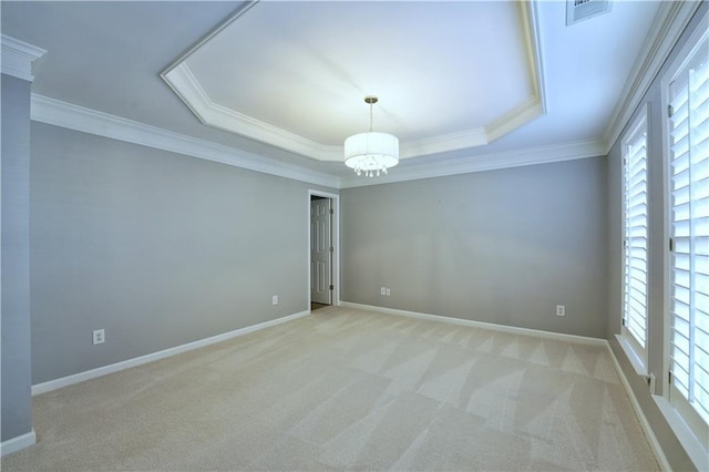 empty room with ornamental molding, a tray ceiling, a notable chandelier, and light colored carpet