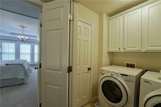 washroom featuring cabinets, washing machine and dryer, and a chandelier